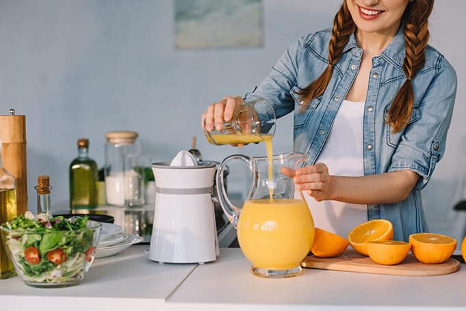 woman preparing and drinking orange juice 